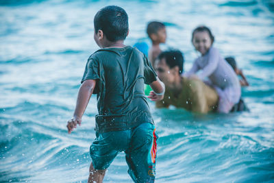 Rear view of boy standing at beach 