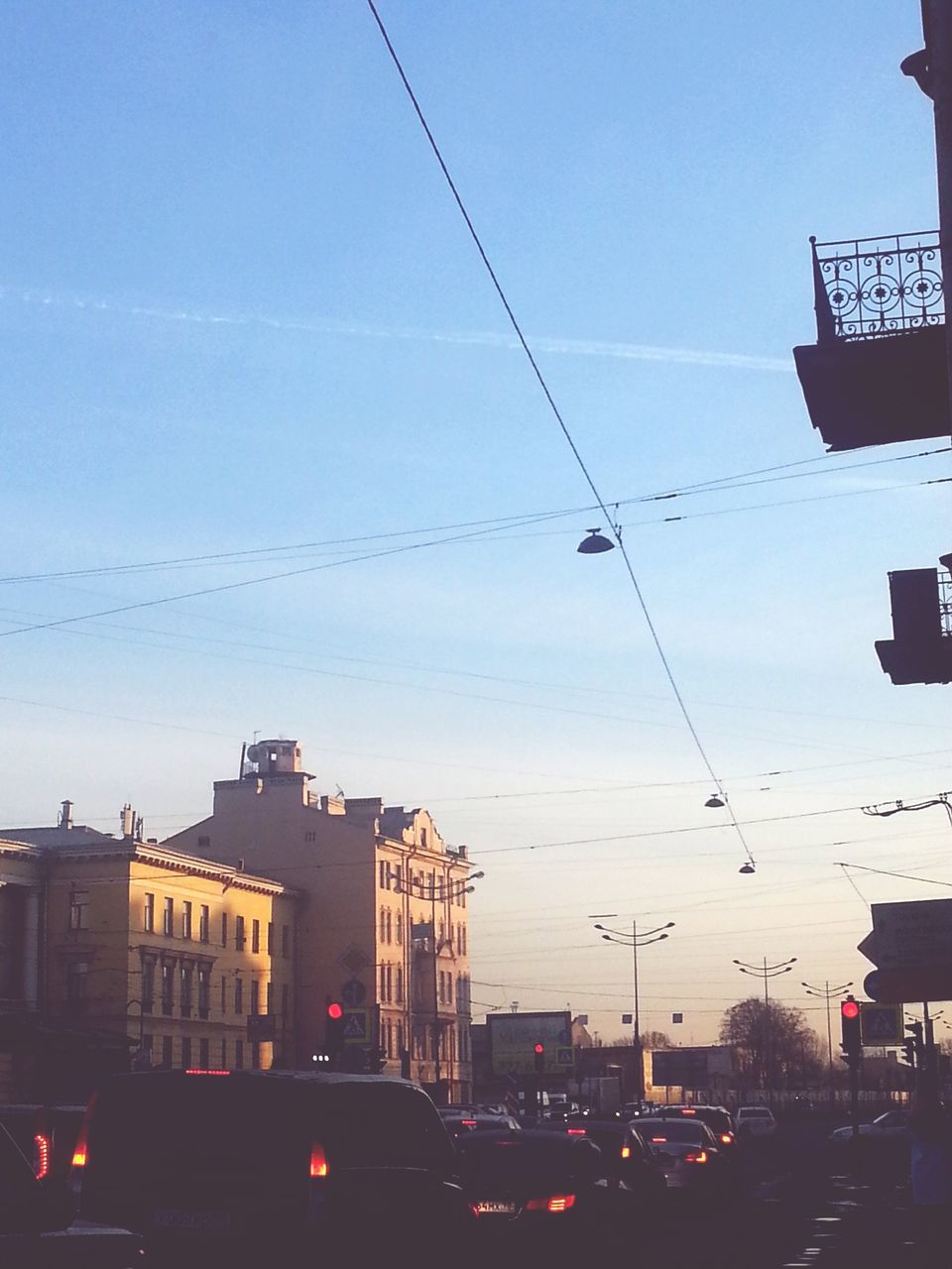 building exterior, architecture, built structure, power line, transportation, car, city, sky, cable, mode of transport, sunset, electricity pylon, street, land vehicle, low angle view, dusk, electricity, silhouette, street light, clear sky