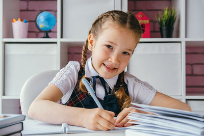Portrait of smiling girl sitting on table at home