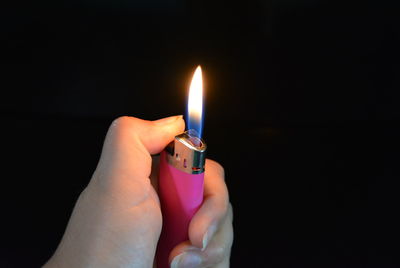 Close-up of hand holding burning candle