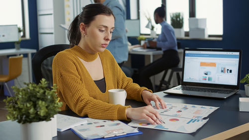 Portrait of young woman using laptop at office