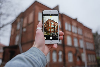 Holds a smartphone in his hand, conducts video filming, photographs for memory