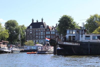 Boats in canal by buildings against clear sky