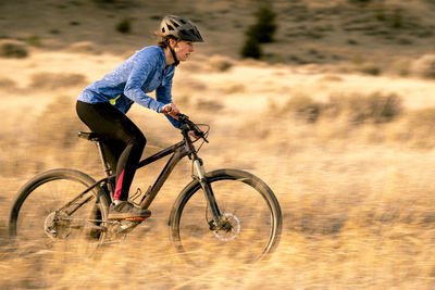 Woman riding downhill mountain biking during sunset