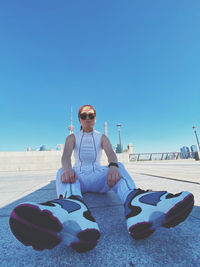 Man sitting in sunglasses against clear sky on sunny day