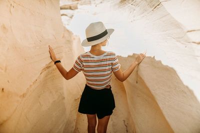 Rear view of woman standing by rock formation