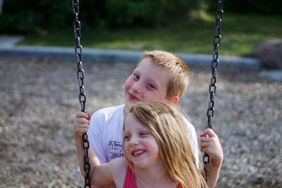 Close-up of happy girl playing with swing in park