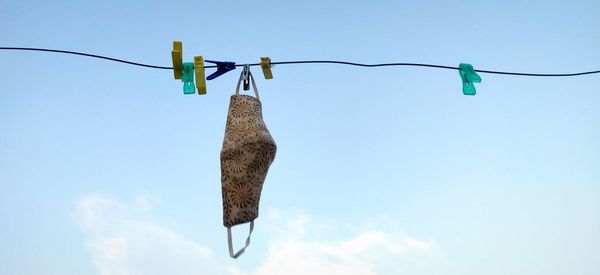 Low angle view of clothes hanging on clothesline against blue sky