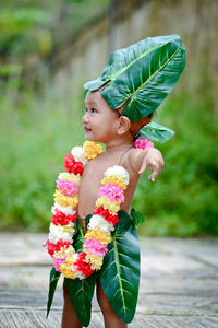 Cute boy wearing leaves and garland standing outdoors