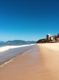 Scenic view of beach against clear blue sky