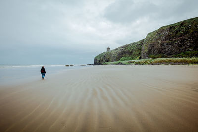 Rear view of person on beach against sky