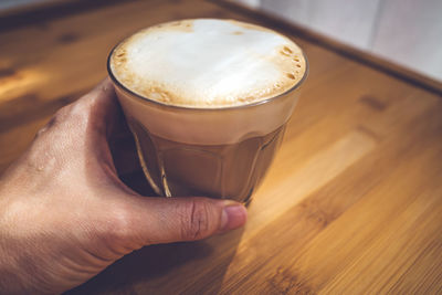 Cropped image of hand holding coffee cup on table