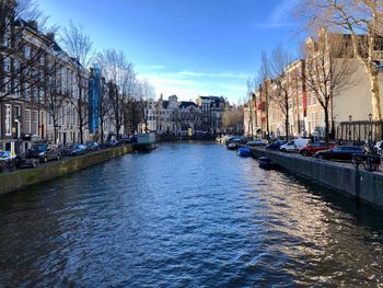 Canal amidst buildings in city against sky