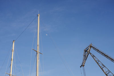 Low angle view of cranes against blue sky