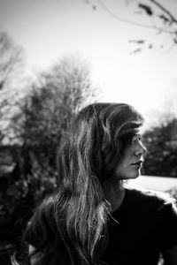 Close-up of woman looking away while standing against bare trees