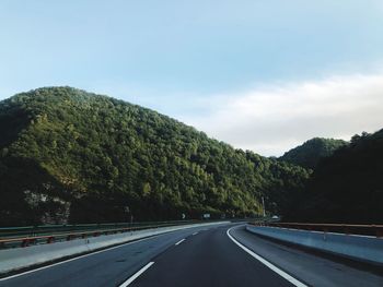 Road by trees against sky