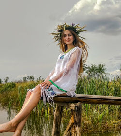 Young woman wearing hat against trees against sky