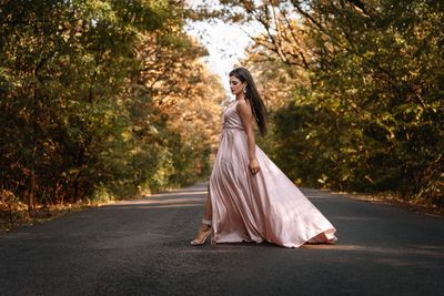 Portrait of woman with umbrella on road against trees