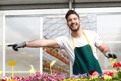 Smiling man pointing while standing in greenhouse