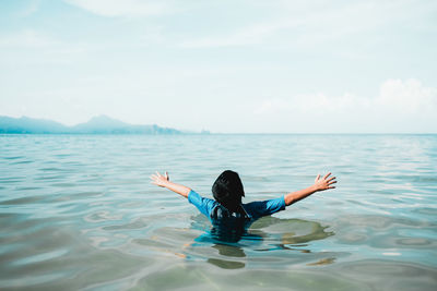 Boy swimming in sea against sky