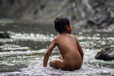 Rear view of shirtless man in sea