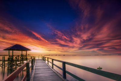 Pier over sea against sky during sunset