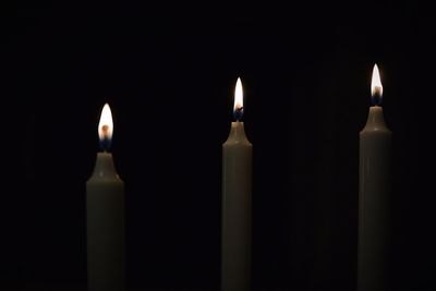 Close-up of lit candles over black background