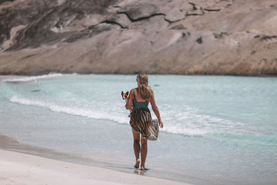 Rear view of woman walking at beach