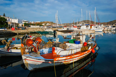 Fishing boats moored at harbor against sky