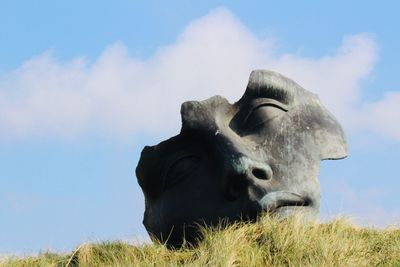 Low angle view of lion statue on field against sky