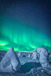 Scenic view of snow covered land against sky during aurora borealis