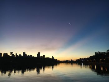 Silhouette trees by lake against sky at sunset