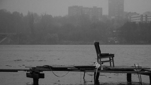 Cranes by river against buildings in city