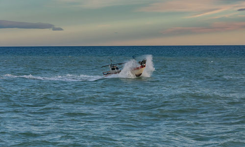 Boat sailing in sea against sky during sunset