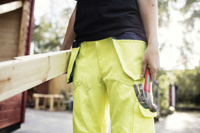 Midsection of carpentry student holding hammer and wooden planks