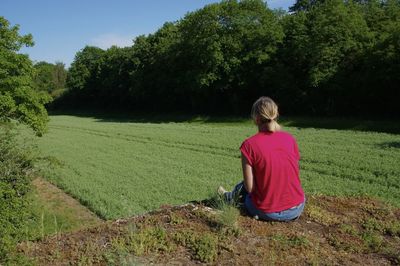 Rear view of woman sitting on land