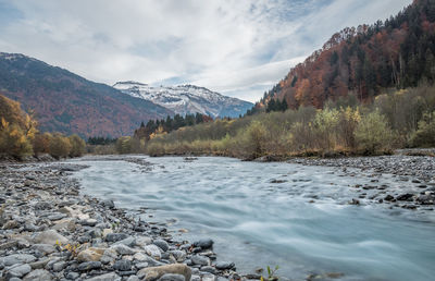 Scenic view of river by mountains against sky