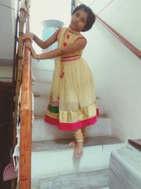 Portrait of young woman standing on staircase