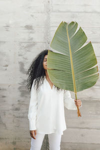 Woman holding umbrella standing against wall