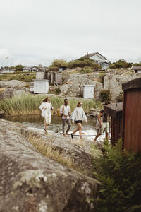 Friends walking on rock by sea at marina during summer vacation