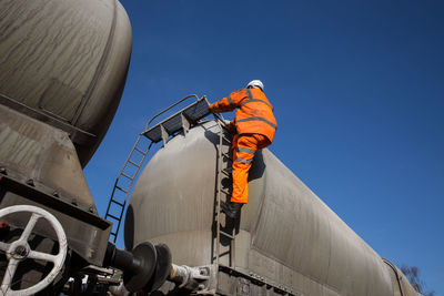 Low angle view of industry against clear blue sky