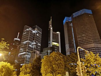 Low angle view of illuminated modern buildings against sky at night