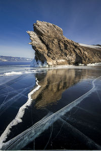 Scenic view of sea by mountain against sky
