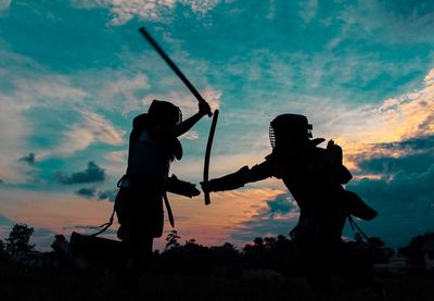 Silhouette people playing against sky during sunset