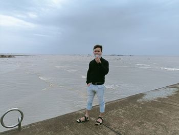 Portrait of man standing on beach against sky