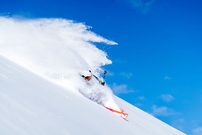 Man skiing on snowcapped mountain against sky