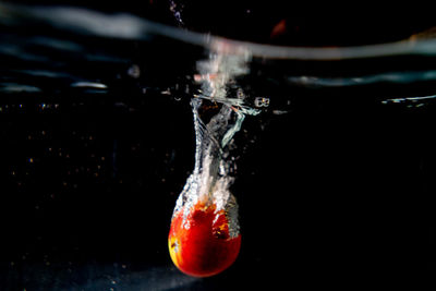 Close-up of water splashing on glass against black background