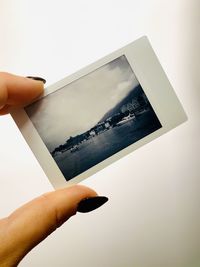 Close-up of hand holding camera against white background