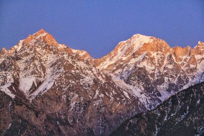 Low angle view of snowcapped mountain against blue sky