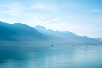 Lake with mountain range in background against cloudy sky